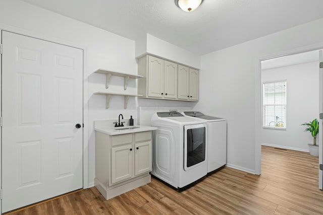 508 Straiton Sq, Westerville, OH 43082 - laundry room with light wood-style flooring, washing machine and clothes dryer, a sink, baseboards, and cabinet space