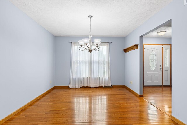 2816 Quail Run Ct, Mansfield, OH 44904 - empty room with light wood-style floors, a chandelier, and a textured ceiling
