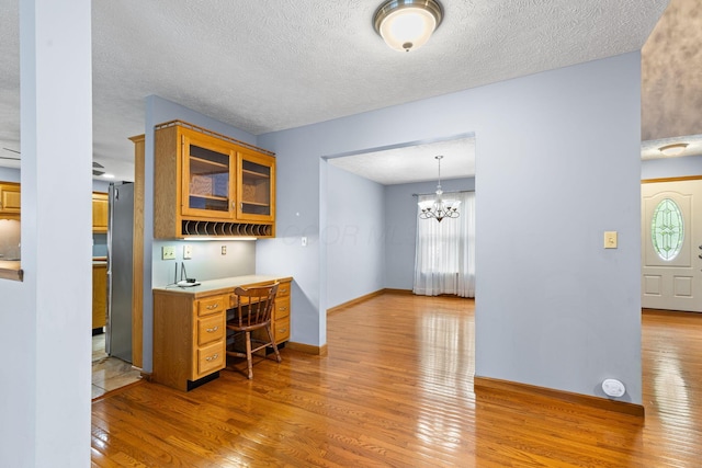 2816 Quail Run Ct, Mansfield, OH 44904 - kitchen featuring light wood finished floors, refrigerator, built in study area, glass insert cabinets, and light countertops