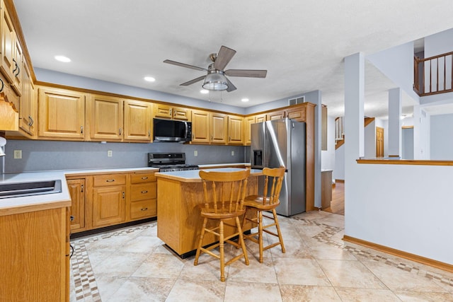 2816 Quail Run Ct, Mansfield, OH 44904 - kitchen featuring appliances with stainless steel finishes, ceiling fan, a kitchen island, light countertops, and a kitchen bar