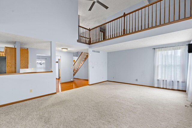 2816 Quail Run Ct, Mansfield, OH 44904 - unfurnished living room with carpet flooring, a chandelier, a towering ceiling, stairs, and ceiling fan