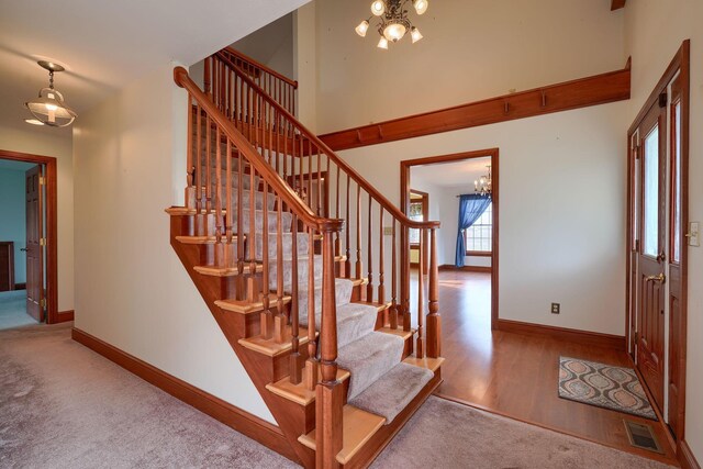 2085 US Highway 62 NE, Washington Court House, OH 43160 - stairs featuring an inviting chandelier, baseboards, a towering ceiling, visible vents, and wood finished floors