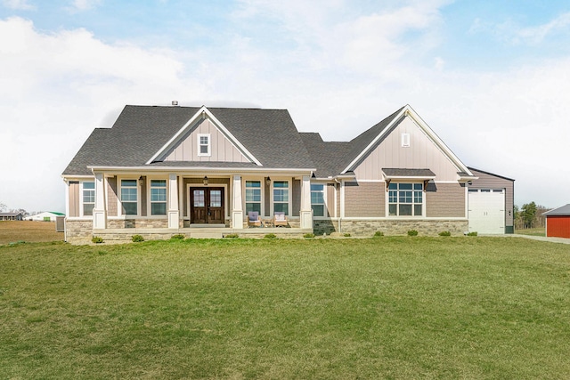 craftsman-style home with stone siding, a front yard, board and batten siding, roof with shingles, and french doors
