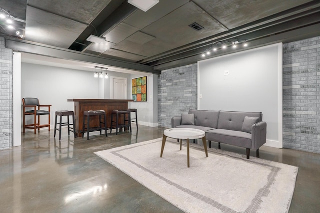 living area featuring visible vents, a bar, concrete floors, rail lighting, and baseboards