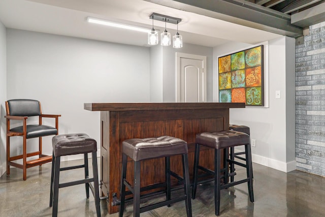 bar featuring concrete floors, a dry bar, and baseboards