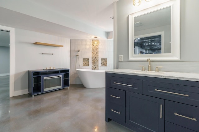 bathroom with vanity, tasteful backsplash, baseboards, finished concrete floors, and a soaking tub