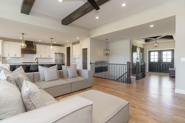 living room featuring light wood finished floors, beamed ceiling, and recessed lighting