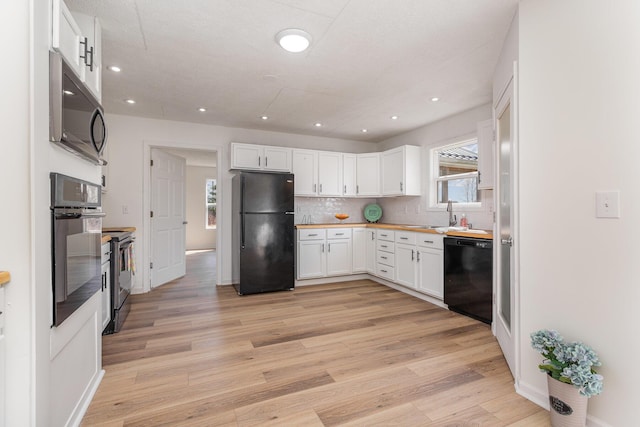 kitchen featuring white cabinetry, light wood-style flooring, black appliances, and backsplash