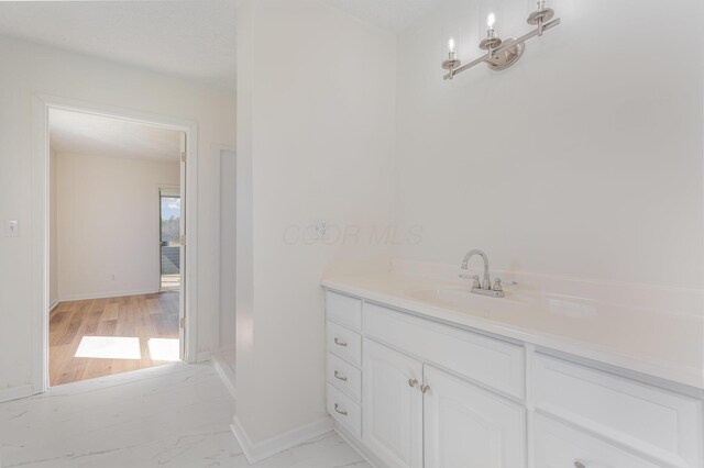 bathroom with marble finish floor, baseboards, and vanity