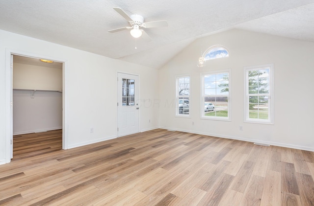 unfurnished bedroom featuring a textured ceiling, light wood-type flooring, and vaulted ceiling
