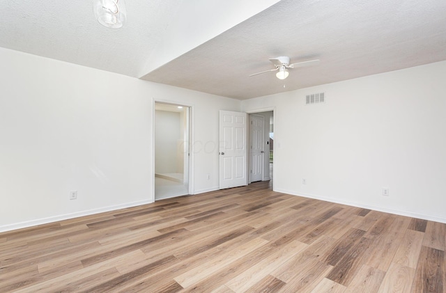 empty room with baseboards, a textured ceiling, ceiling fan, light wood-style flooring, and visible vents