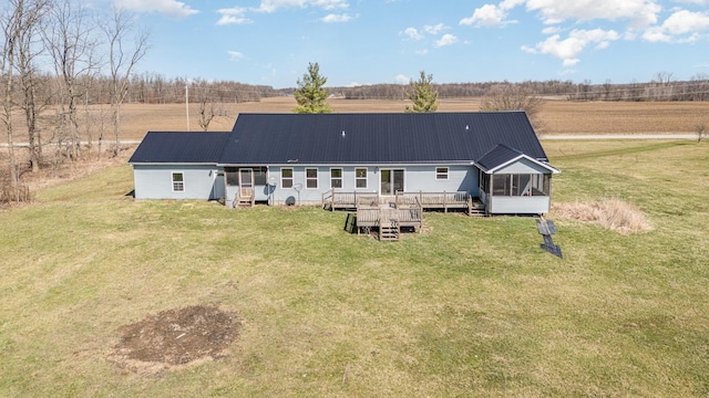 rear view of house featuring a sunroom, metal roof, a deck, and a yard