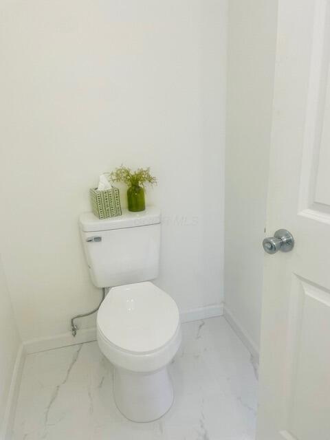bathroom with baseboards, marble finish floor, and toilet