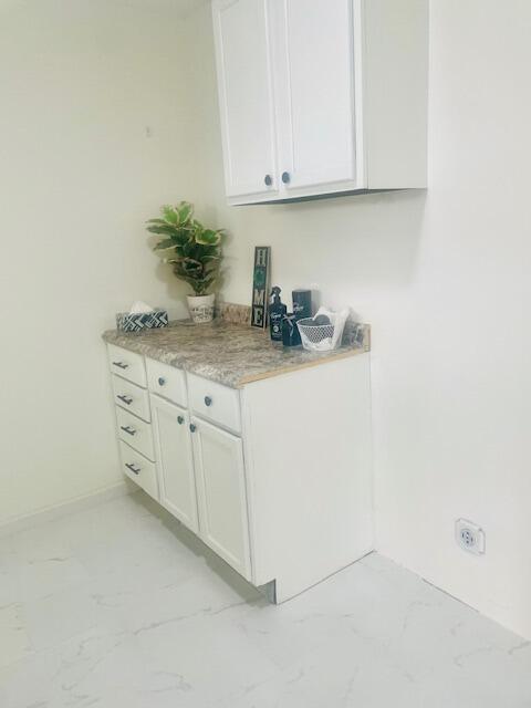 bar featuring marble finish floor and baseboards