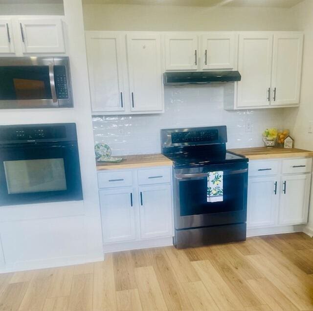 kitchen featuring white cabinetry, light wood-type flooring, stainless steel appliances, under cabinet range hood, and backsplash
