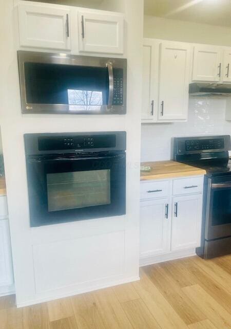 kitchen with light wood finished floors, white cabinets, under cabinet range hood, and appliances with stainless steel finishes
