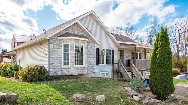 view of front facade featuring stone siding, stairs, and a front yard