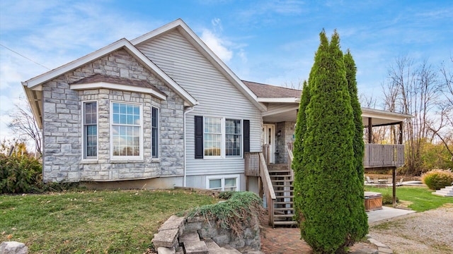 view of front of house featuring stone siding, stairs, and a front yard