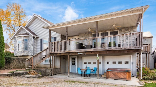 back of house featuring stone siding, a ceiling fan, a hot tub, and stairs
