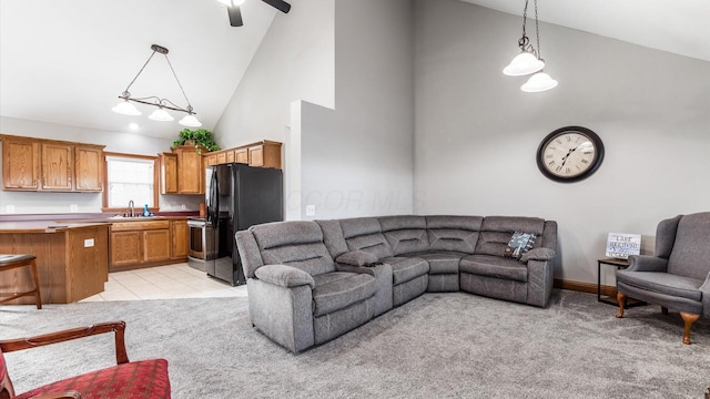 living area featuring baseboards, high vaulted ceiling, ceiling fan, and light colored carpet