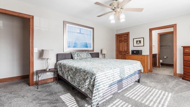 carpeted bedroom with baseboards, ensuite bath, and a ceiling fan