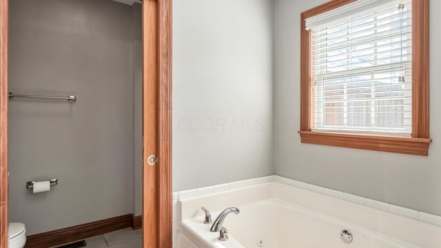 full bath featuring a whirlpool tub, toilet, tile patterned flooring, and baseboards