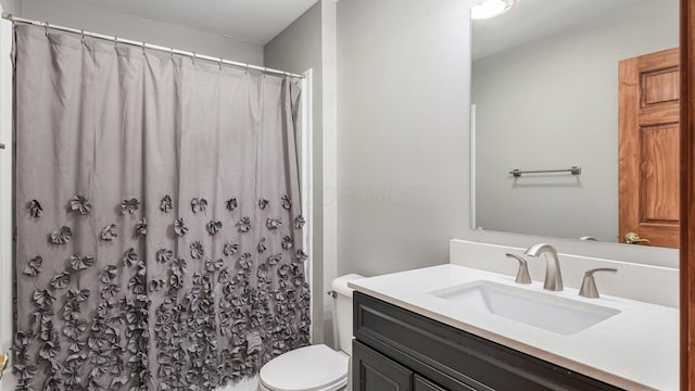 bathroom featuring curtained shower, toilet, and vanity