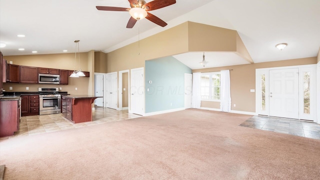 kitchen with open floor plan, light colored carpet, stainless steel appliances, dark countertops, and a ceiling fan