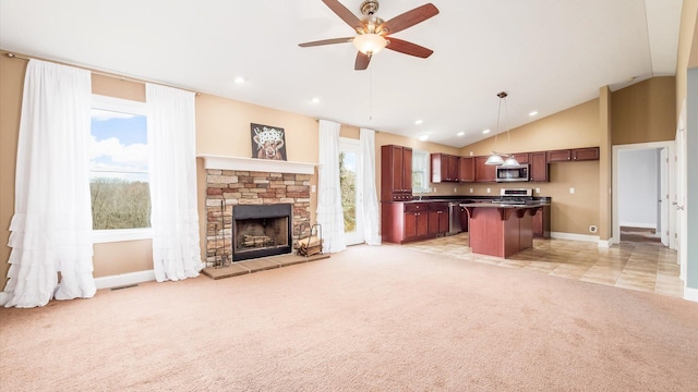 unfurnished living room featuring a ceiling fan, a stone fireplace, baseboards, light colored carpet, and visible vents