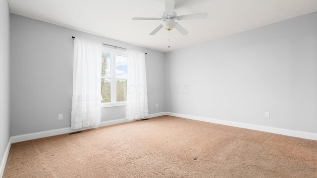 carpeted spare room featuring baseboards, visible vents, and a ceiling fan