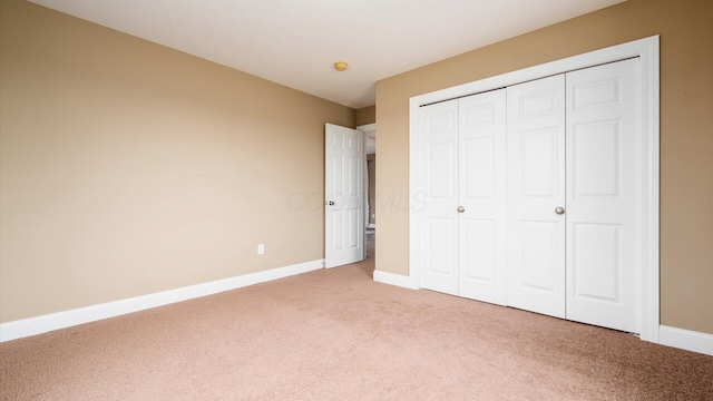 unfurnished bedroom featuring baseboards, a closet, and light colored carpet