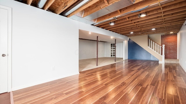 finished below grade area featuring baseboards, wood finished floors, and stairway