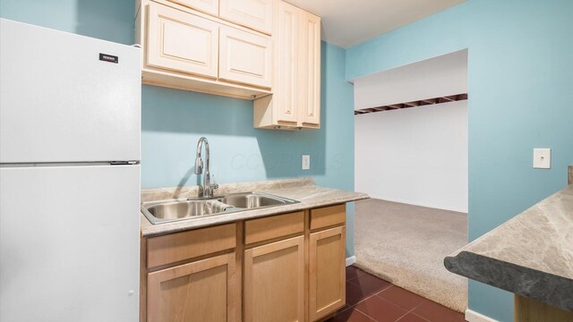kitchen featuring light countertops, a sink, freestanding refrigerator, dark carpet, and dark tile patterned flooring