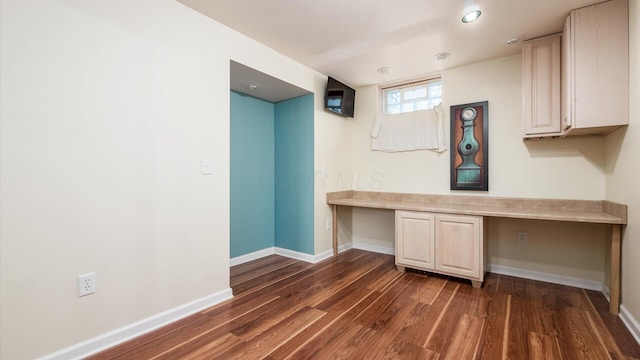 unfurnished office featuring dark wood finished floors, baseboards, and built in study area