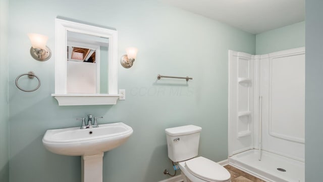 full bathroom featuring toilet, tile patterned floors, baseboards, and a shower stall