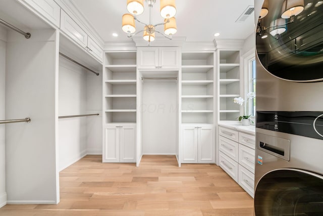 2252 Club Rd, Upper Arlington, OH 43221 - walk in closet featuring light wood finished floors, visible vents, stacked washer / dryer, and a notable chandelier