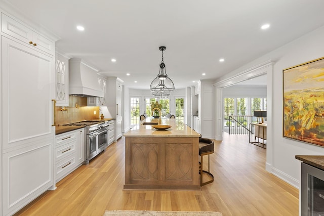 2252 Club Rd, Upper Arlington, OH 43221 - kitchen with light wood finished floors, wine cooler, double oven range, custom exhaust hood, and white cabinetry