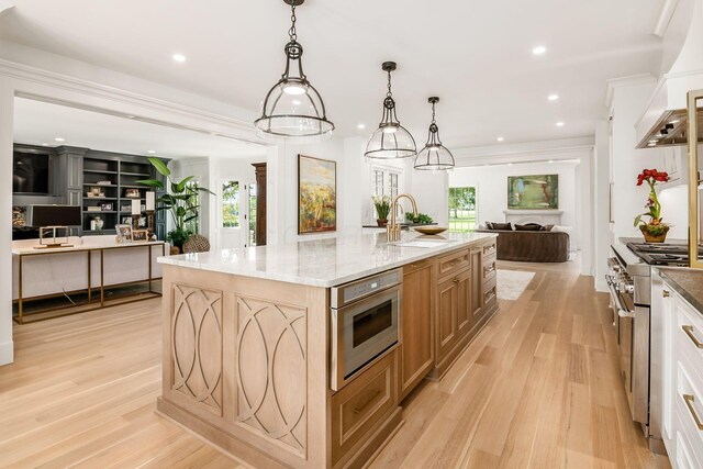 2252 Club Rd, Upper Arlington, OH 43221 - kitchen featuring a large island with sink, a sink, light wood-style floors, stainless steel stove, and open floor plan