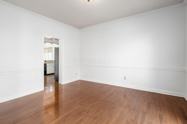 empty room featuring dark wood-type flooring, baseboards, and crown molding