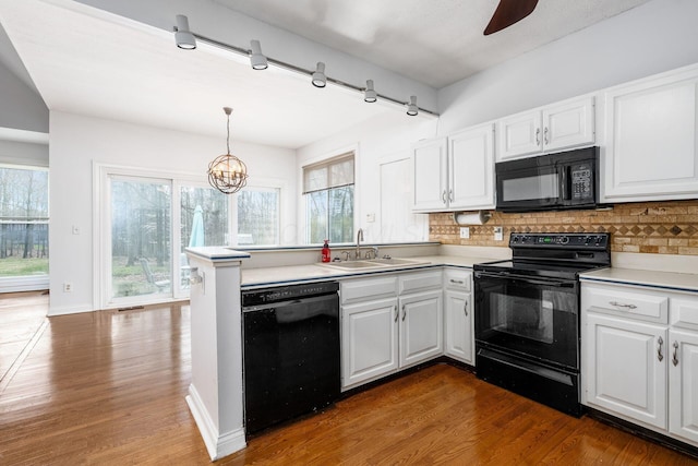 kitchen featuring dark wood-style flooring, white cabinetry, a sink, black appliances, and backsplash