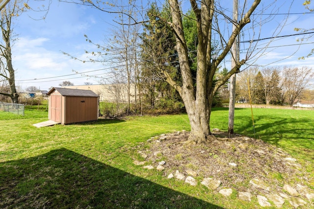 view of yard featuring an outbuilding, a storage unit, and fence