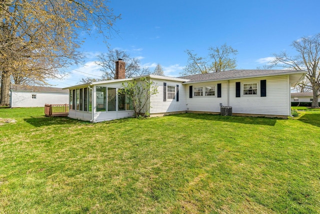 back of property with a yard, central AC, a sunroom, and a chimney