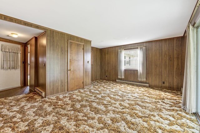 interior space with a baseboard radiator, carpet flooring, and wooden walls
