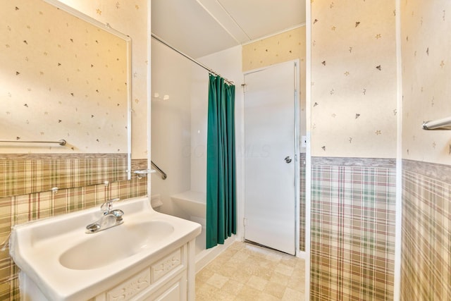 full bath with vanity, curtained shower, wainscoting, and wallpapered walls