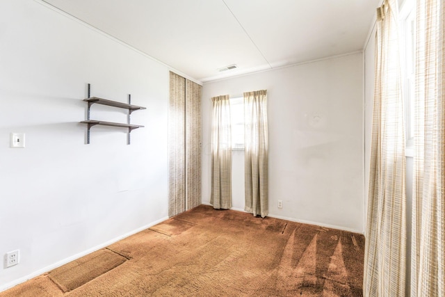 empty room with crown molding, carpet flooring, baseboards, and visible vents