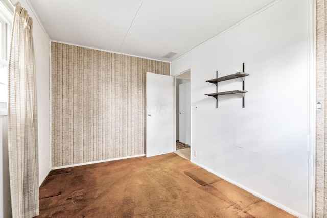 empty room featuring visible vents, baseboards, crown molding, wallpapered walls, and carpet flooring