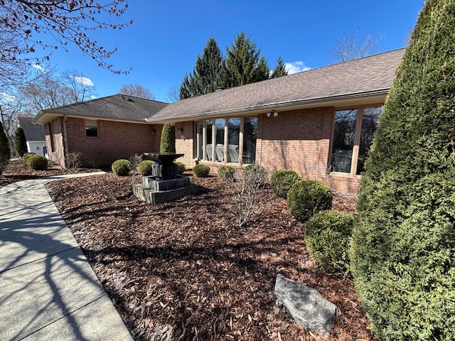 view of front of home with brick siding and roof with shingles