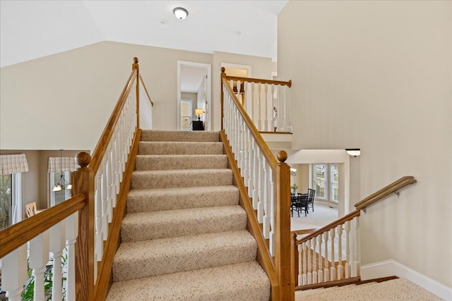 stairs featuring high vaulted ceiling and baseboards