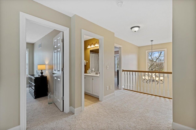 hall featuring light carpet, a notable chandelier, a sink, and visible vents