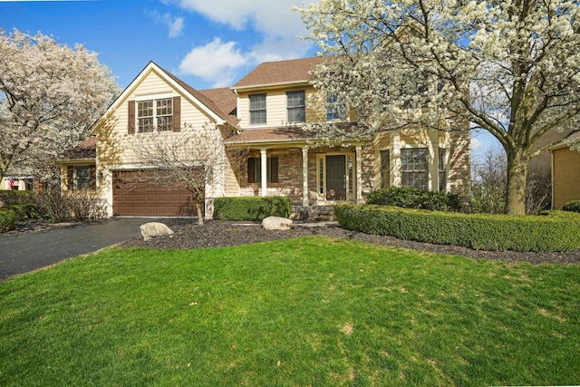 traditional home featuring driveway, stone siding, an attached garage, and a front lawn